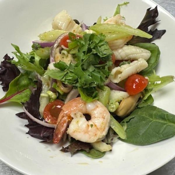 A vibrant Thai seafood salad with shrimp, squid, mussels, mixed greens, red onion, and cherry tomatoes.