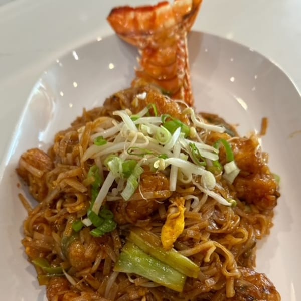 Lobster Pad Thai with bean sprouts and scallions, served on a white plate at West - 365 Thai & Sushi.