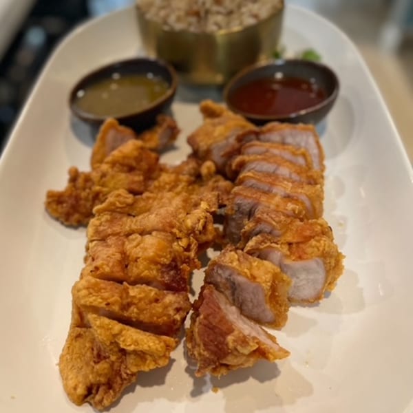 Crispy fried pork belly slices with two dipping sauces and a bowl of rice.